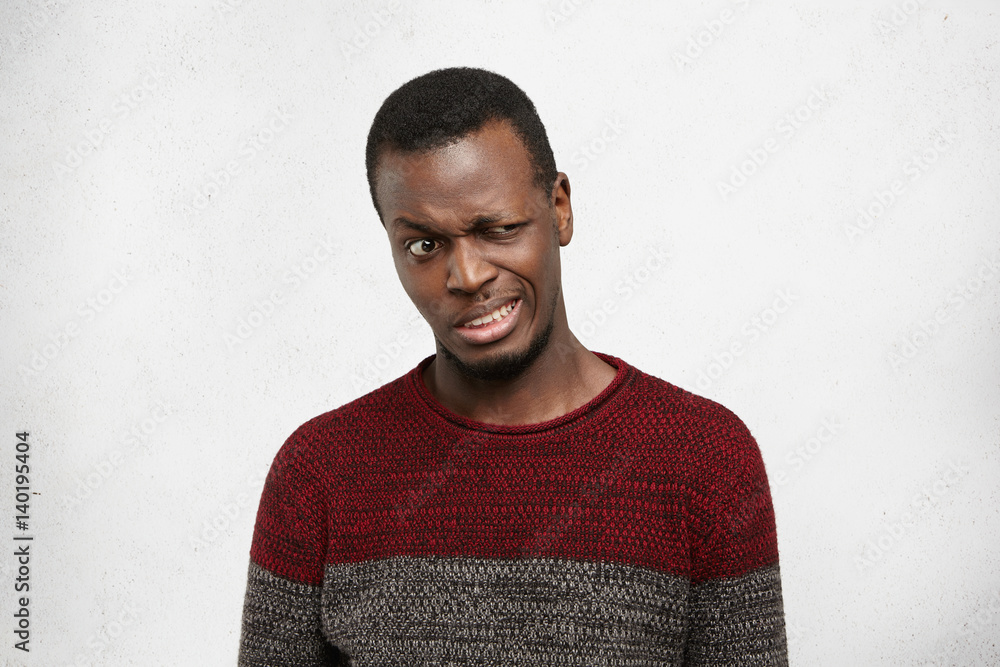 Human facial expressions, emotions and feelings. Studio shot of disgusted young African American man dressed casually, grimacing, looking in terror and disgust, feeling averse to do something Human facial expressions, emotions and feelings. Studio shot of disgusted young African American man dressed casually, grimacing, looking in terror and disgust, feeling averse to do something