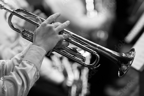 Hands of man playing the trumpet in the orchestra in black and white