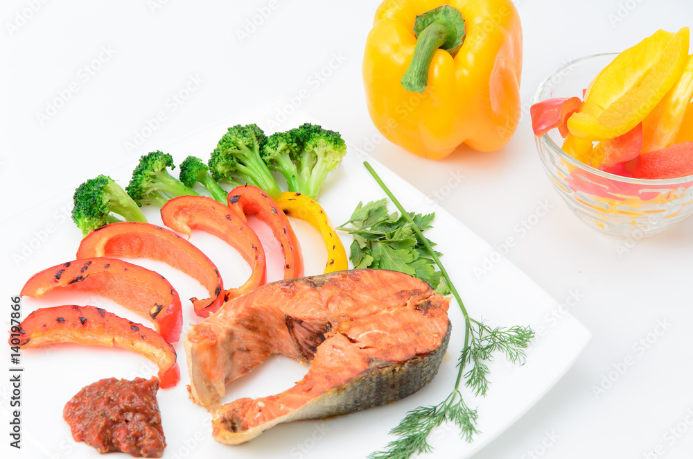 Grilled red fish with sauce, broccoli, parsley and dill on a white plate Grilled red fish with sauce, broccoli, parsley and dill on a white plate