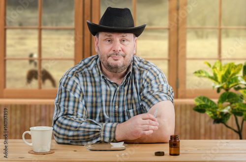Mature farmer in black hat holds syringe for injection