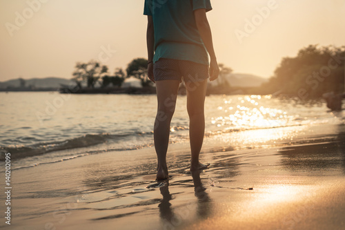 Young woman traveller walking on the beach at beautiful sunset