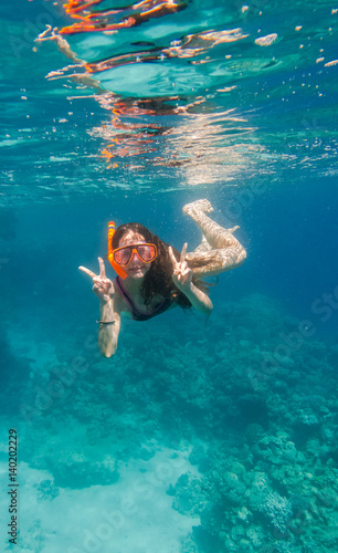 Girl in swimming mask dive underwater near coral reef 