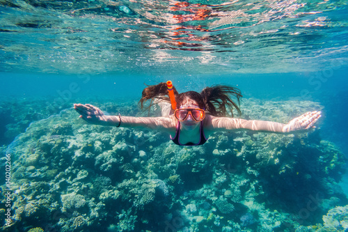 Girl in swimming mask diving in Red sea near coral reef