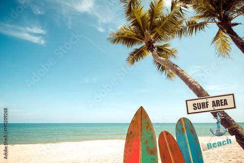 Photography Vintage surf board with palm tree on tropical beach in summer