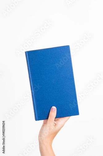 CLose up of female caucasian female woman holding blue book isolated on white background. Vertical color point of view shot