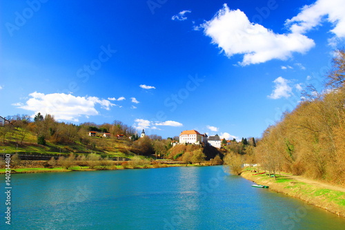 River landscape, boat on coast, village with castle in background, Ozalj in Croatia photo