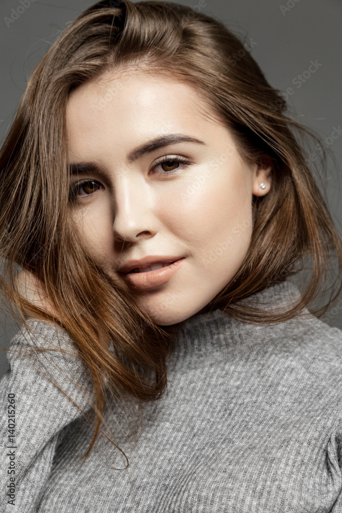 Smiling cute girl with clear skin looking at the camera on gray background Smiling cute girl with clear skin looking at the camera on gray background