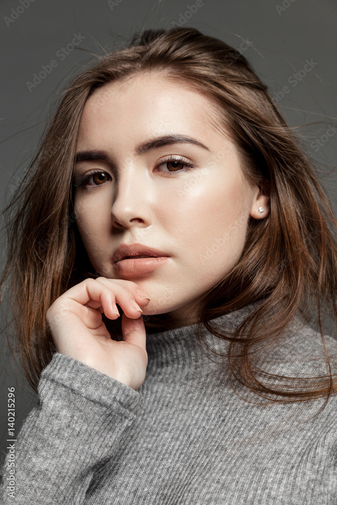 Naklejka premium Cute young model woman with clear skin looking at the camera on gray background