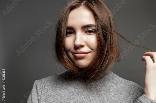 Portrait of smiling young woman looking at the camera on gray background.