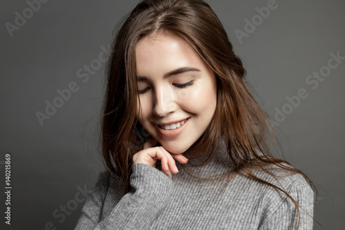 Happy smiling young model woman with clear skin looking at the camera on gray background