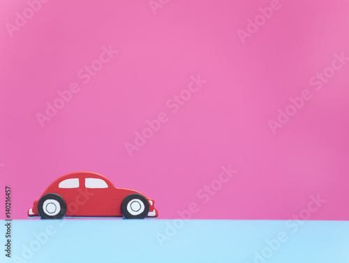 cute red car shaped toy in front of wonderful pink background