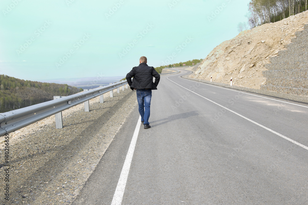 Fototapeta premium Man walking on a mountain road to his dream