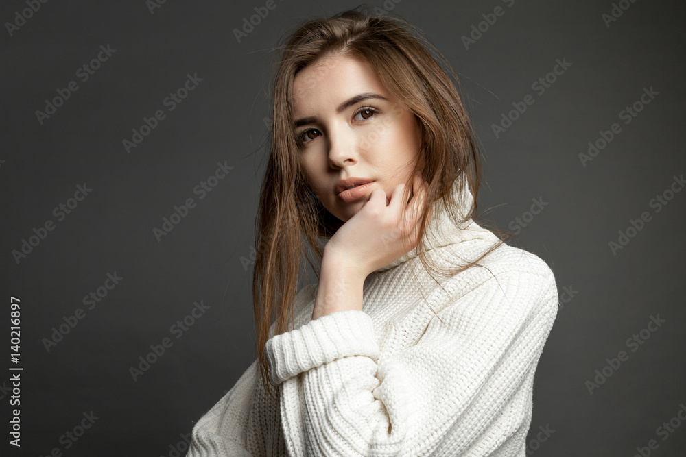 Girl model in white sweater on a gray background looking at the camera Girl model in white sweater on a gray background looking at the camera