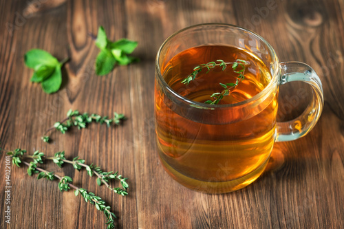 The Cup of tea on wooden background with mint leaves and thyme