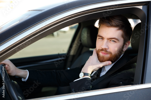 Pensive business man holding hand on chin and driving car