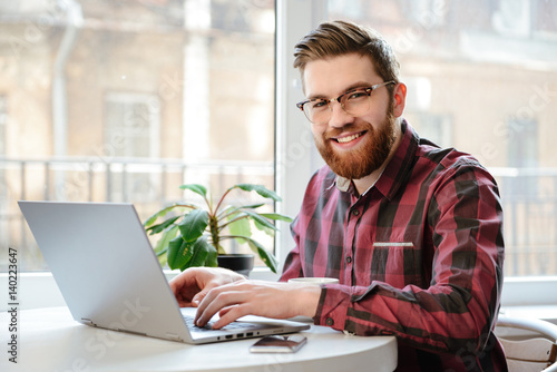 Bearded young man using laptop computer.