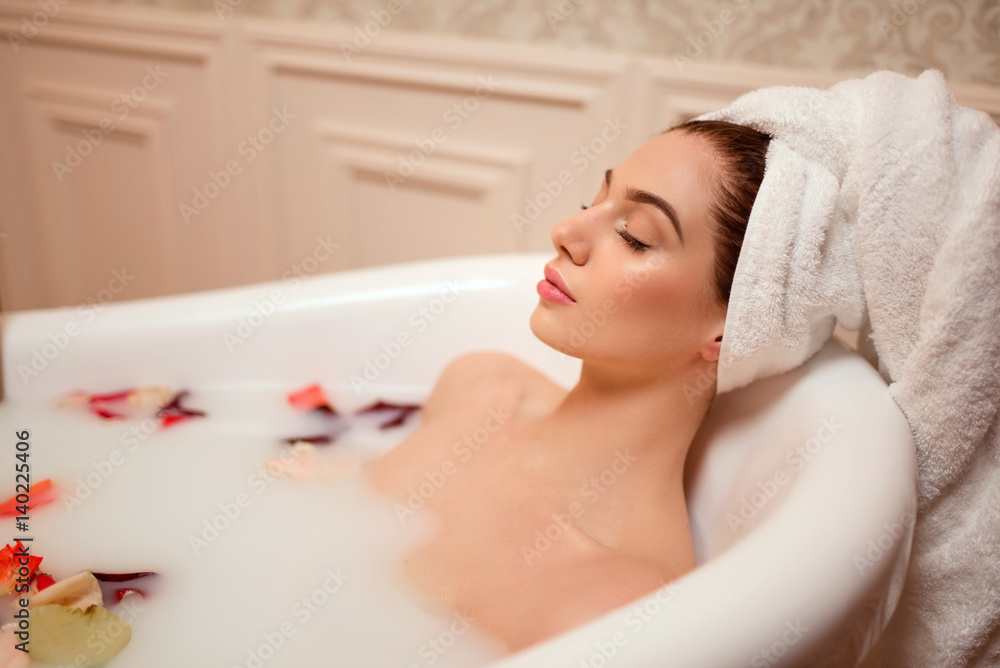 Woman in bathroom with rose petals and foam. Woman in bathroom with rose petals and foam.