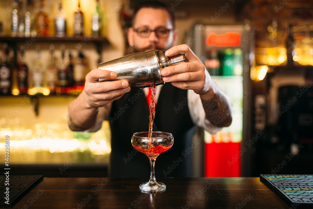 Barman is making alcohol cocktail at counter