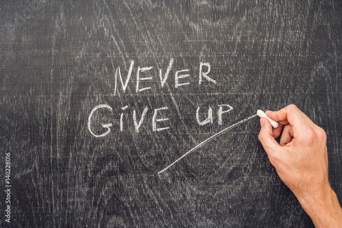 Never give up words written on the chalkboard photo