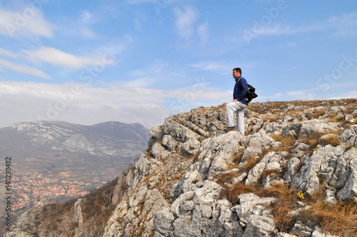 Young man standing on a cliff edge  on the top of mountain with gorgeous view