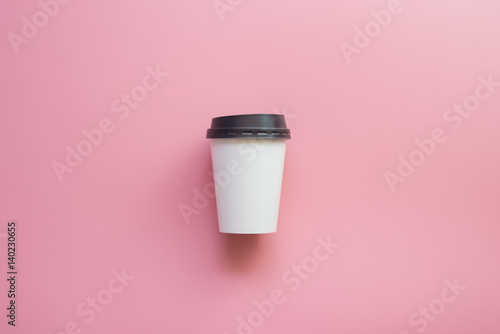 Flat lay design of hot coffee cup on pink pastel background.