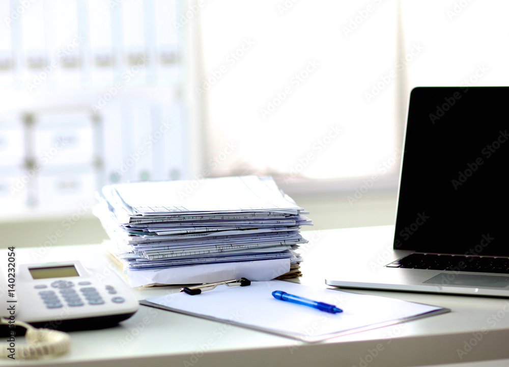 A note book, laptop, pen, graph paper document on the office desk table behind white blind A note book, laptop, pen, graph paper document on the office desk table behind white blind