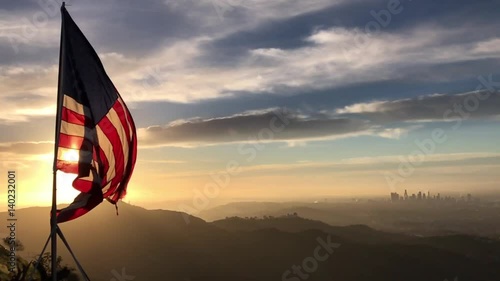American flag flying in the wind at sunrise over the city of Los Angeles slow motion