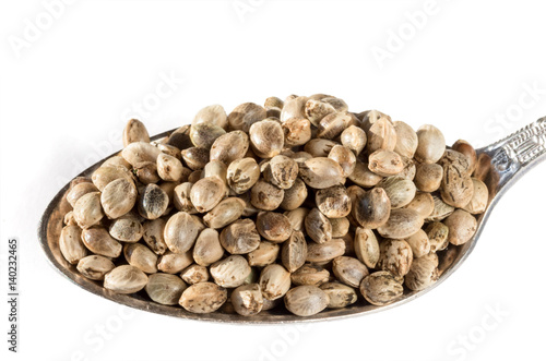 Marijuana seeds in a metal measuring spoon isolated on white background.