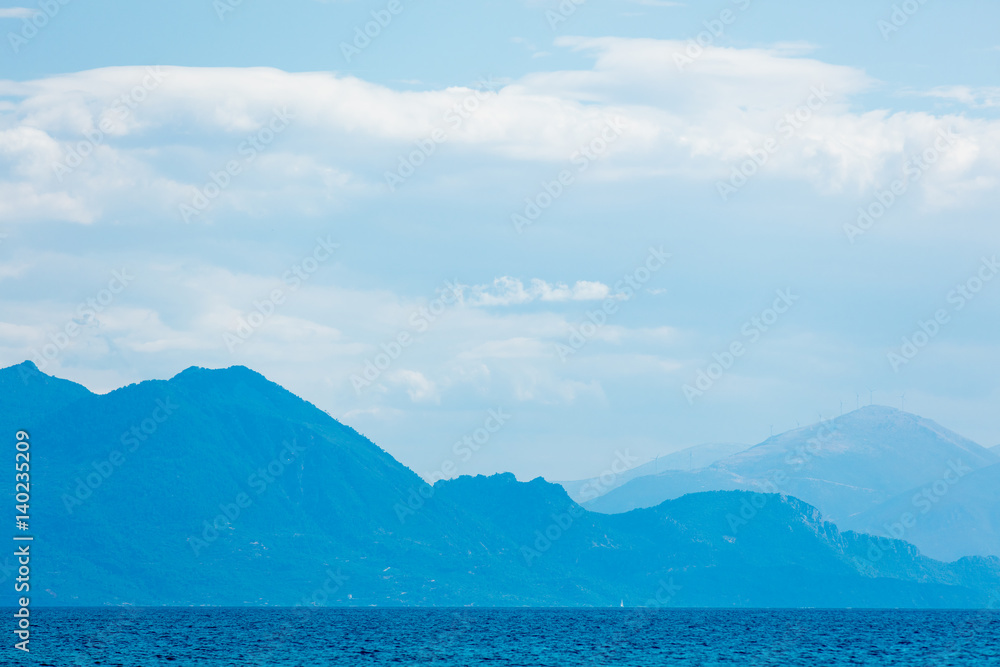 photo of the cute small ship in the distance in the sea on the mountains background in Greece