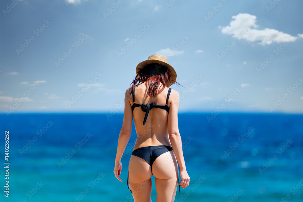 beautiful young woman standing on the coast and looking at the sea in Greece