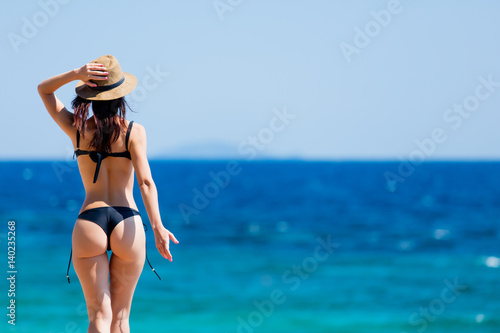 beautiful young woman standing on the coast and looking at the sea in Greece