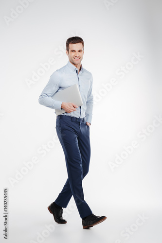 Vertical image of smiling business man walking with laptop © Drobot Dean