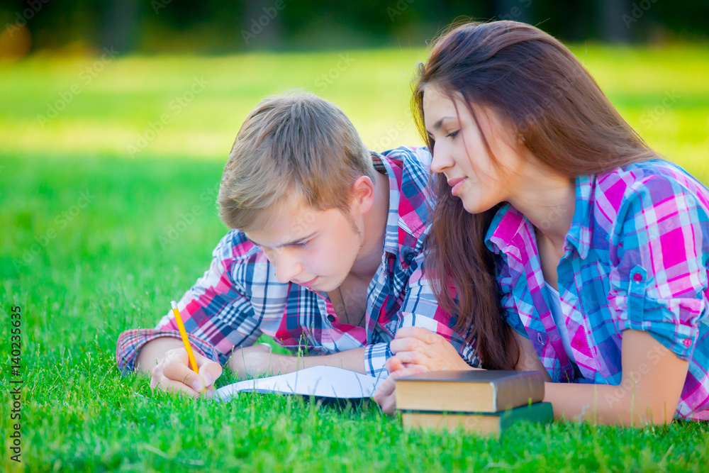beautiful cute couple lying on the field and studing with books beautiful cute couple lying on the field and studing with books