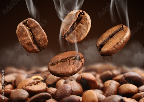 Closeup falling coffee bean with steam on brown background