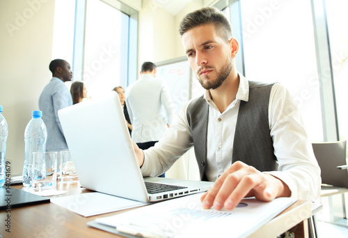 Handsome businessman working with laptop in office.
