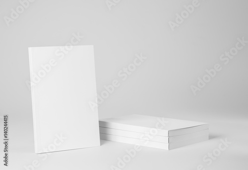 Real paperback white book next to a stack of books on a gray background photo