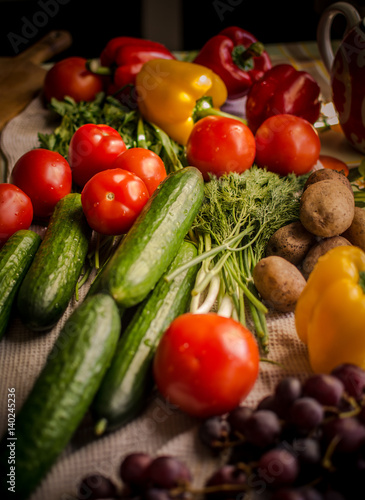 Various vegetables and fruits, bright colors, are on the kitchen table. 