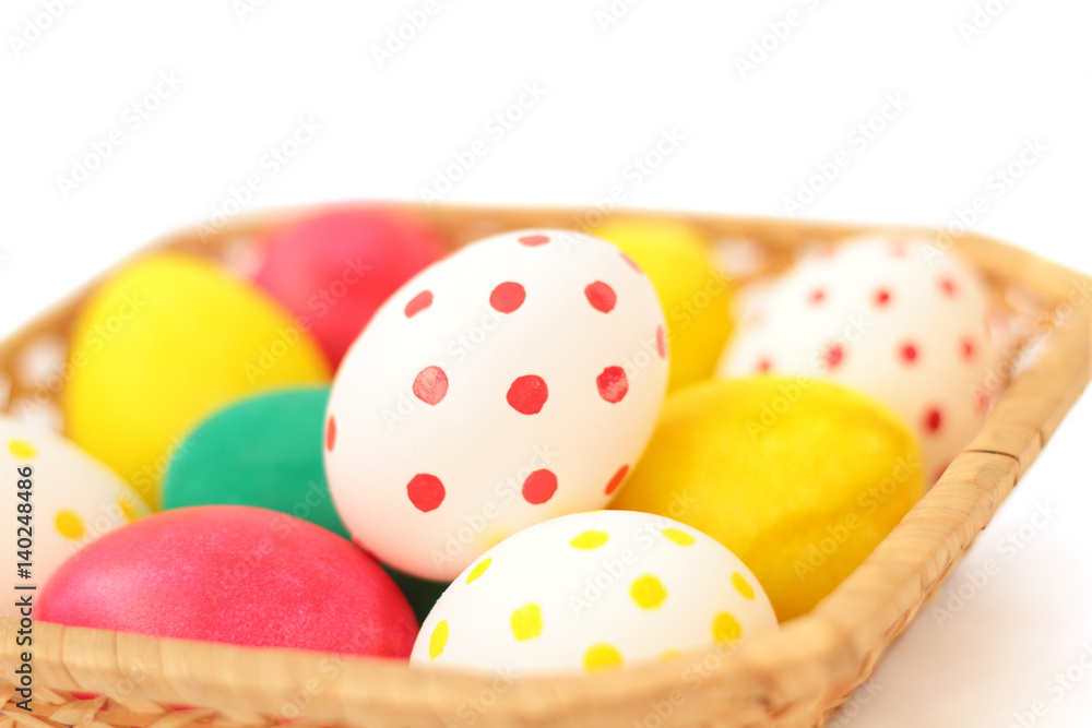 Fototapeta premium Easter basket filled with colorful eggs on a white background