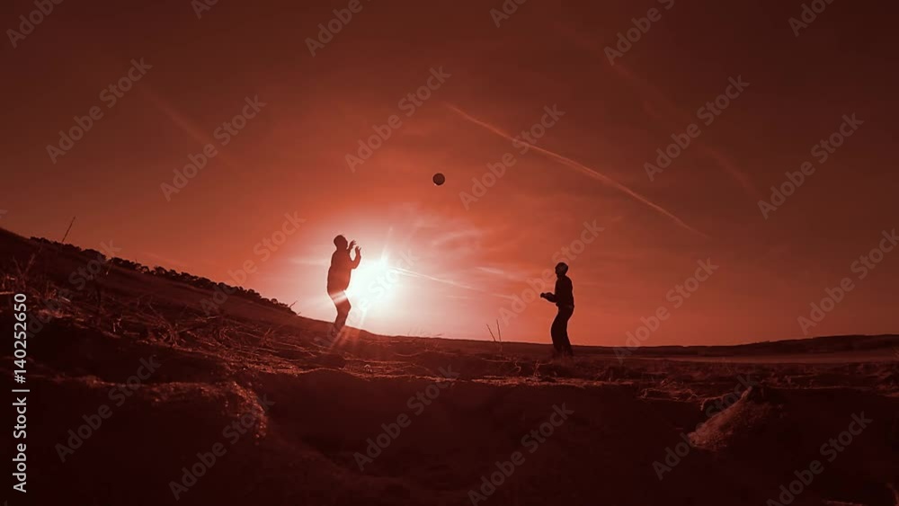 Two men playing volleyball on the beach sunset sport silhouettes Two men playing volleyball on the beach sunset sport silhouettes