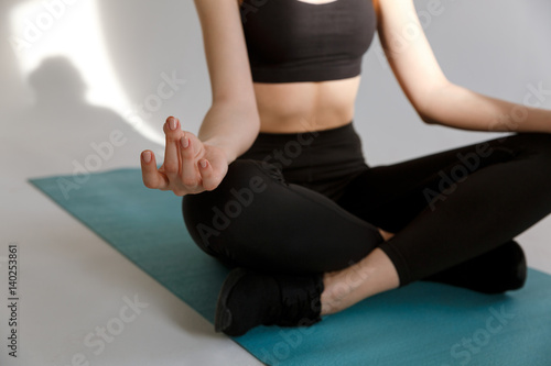Young woman sitting in lotus yoga pose on mat