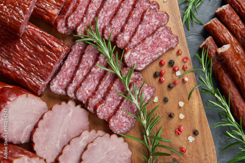 Fotografie Set of cold cuts on a wooden board. Mix of sausages