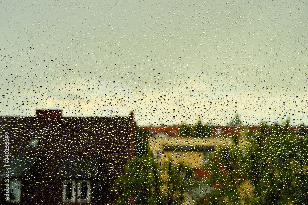 Krople deszczu na szybie, w tle dachy domów. - obrazy, fototapety, plakaty 