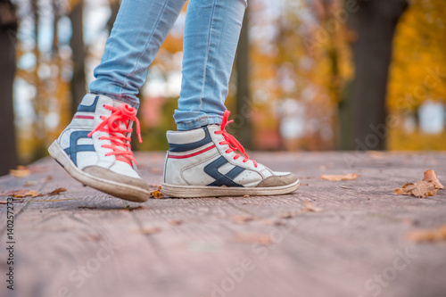 Feet teen in shoes with orange laces  a walk in the autumn Park.