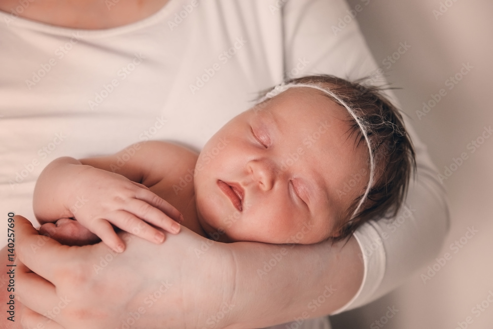 A newborn infant sleeping in the parent's hands. A newborn infant sleeping in the parent's hands.
