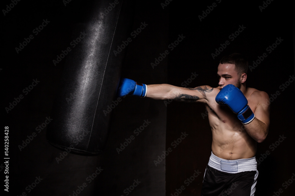 Athlete boxer man punching a punching bag