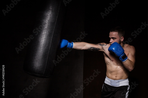 Athlete boxer man punching a punching bag © Iryna