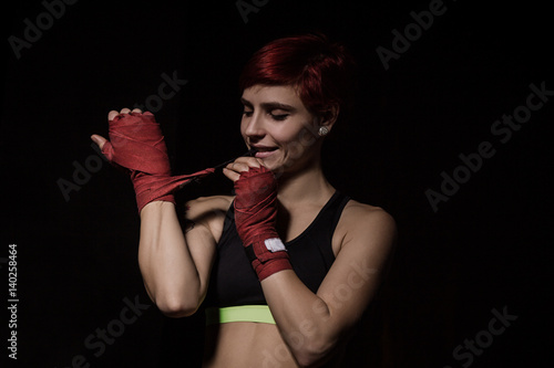 Woman is wrapping hands with red boxing wraps