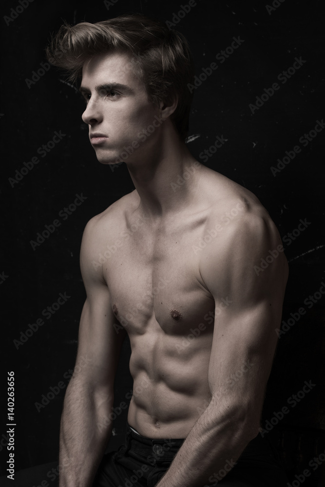 Fototapeta premium Young Handsome man with great fit body posing at the chair 