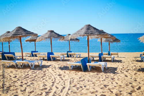 Straw umbrellas on ocean beach in Algarve Portugal  sunny outdoors background