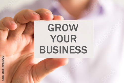 Businessman holding a card with GROW YOUR BUSINESS message